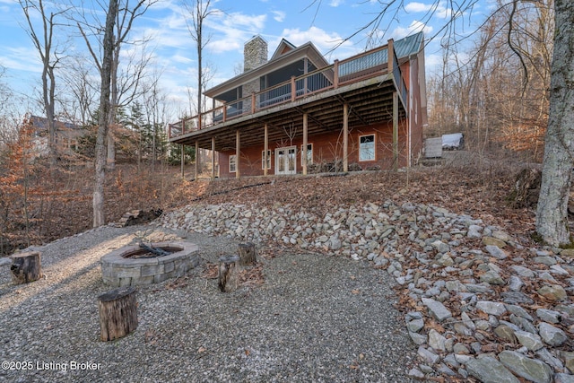 view of front of home with a deck, a fire pit, and a chimney