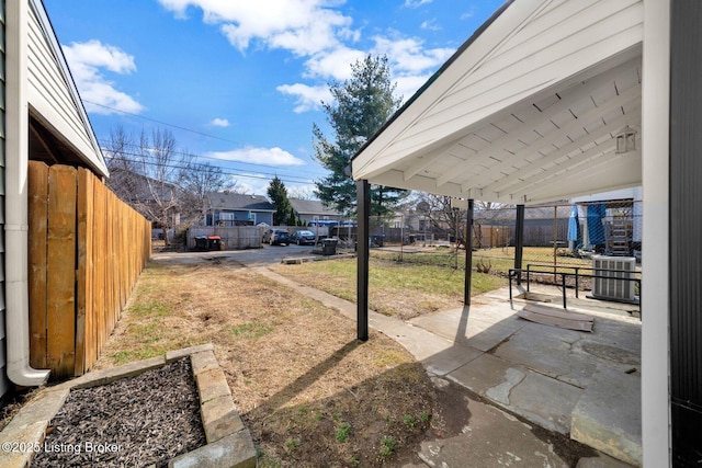 view of yard with central AC unit, fence, a residential view, and a patio area