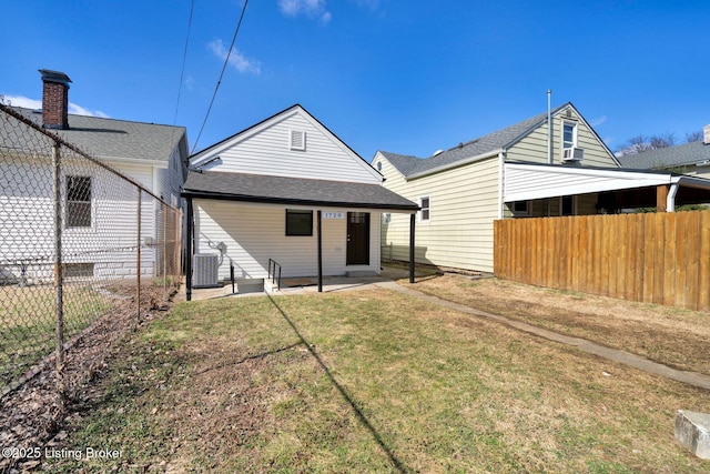 back of house with fence, central air condition unit, roof with shingles, a yard, and a patio area