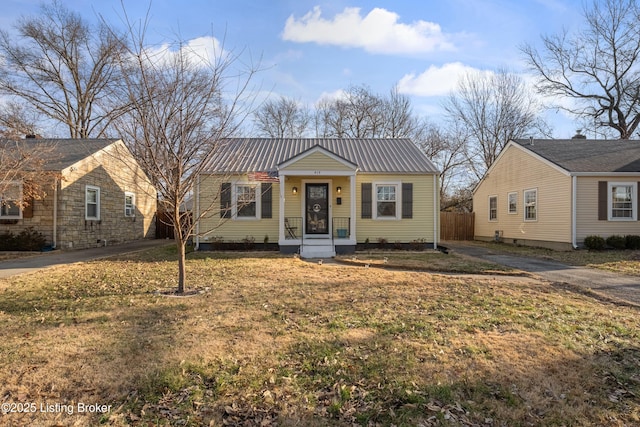 bungalow-style home with metal roof, a front lawn, driveway, and fence