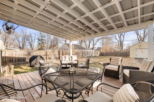 wooden terrace featuring an outdoor living space, area for grilling, a fenced backyard, and an outbuilding