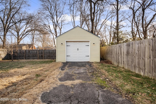 detached garage featuring fence and driveway