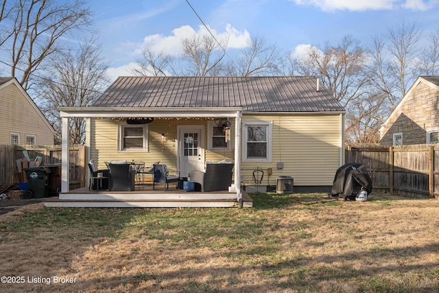 rear view of property featuring fence, a wooden deck, a lawn, cooling unit, and metal roof