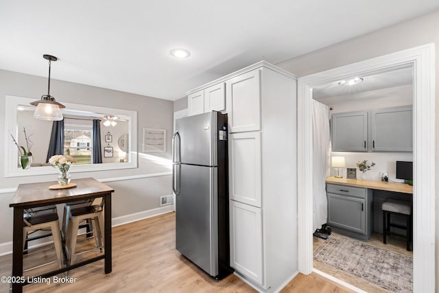 kitchen with light wood-style floors, baseboards, freestanding refrigerator, and built in study area