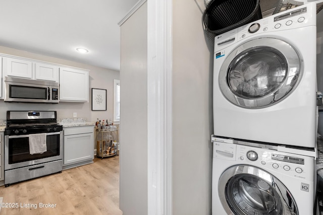 laundry area with light wood-style flooring and stacked washing maching and dryer