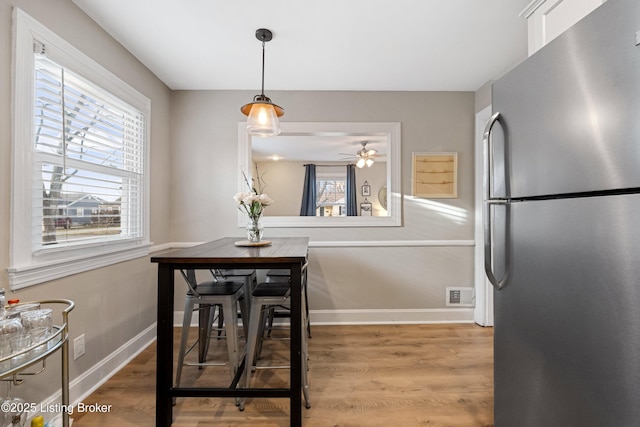 dining space featuring visible vents, ceiling fan, baseboards, and wood finished floors