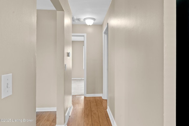 corridor with baseboards and light wood finished floors