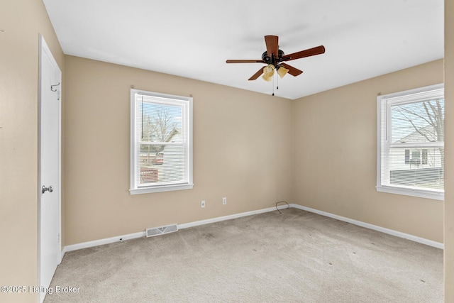 empty room featuring carpet flooring, a ceiling fan, visible vents, and baseboards