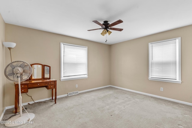 carpeted empty room with a wealth of natural light, visible vents, baseboards, and a ceiling fan