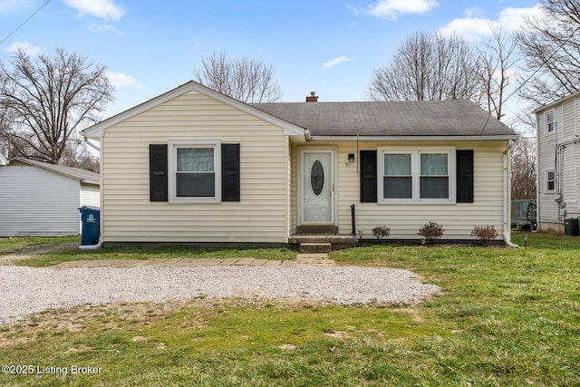 view of front of home with entry steps, a front yard, and a shingled roof