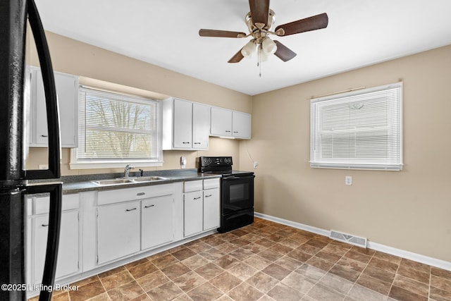 kitchen featuring baseboards, visible vents, a sink, black appliances, and dark countertops