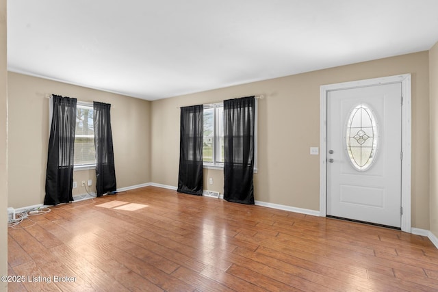 foyer with wood finished floors, visible vents, and baseboards