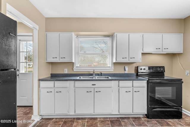 kitchen with a sink, dark countertops, black appliances, and white cabinetry