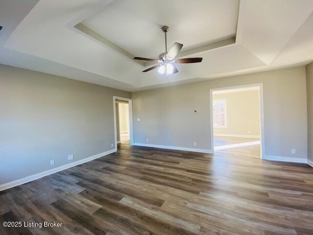 spare room with ceiling fan, baseboards, a raised ceiling, and wood finished floors