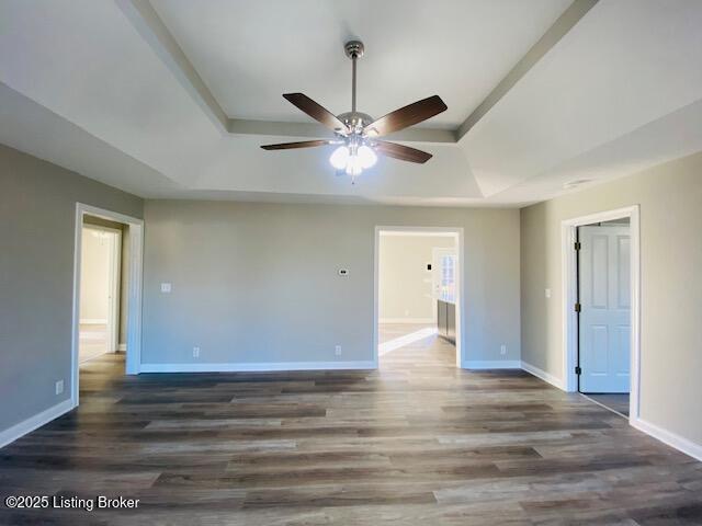 unfurnished room with a ceiling fan, a raised ceiling, wood finished floors, and baseboards