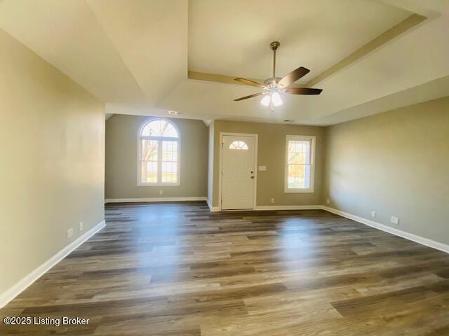 foyer entrance with a raised ceiling, wood finished floors, baseboards, and ceiling fan