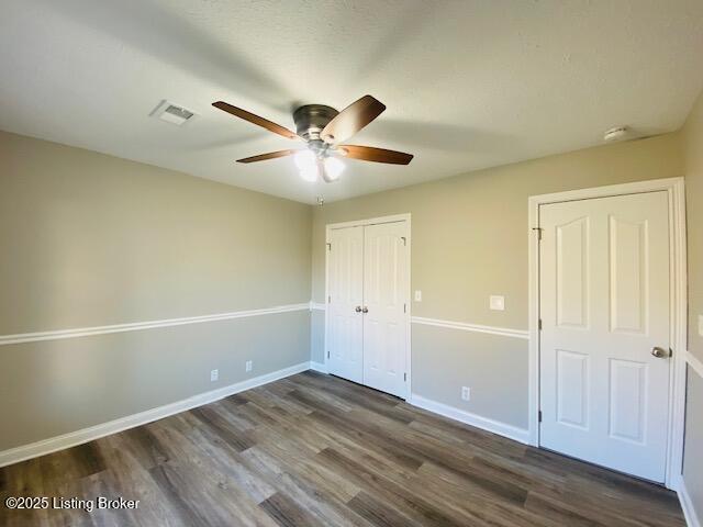 unfurnished bedroom featuring visible vents, baseboards, a closet, and dark wood-style floors