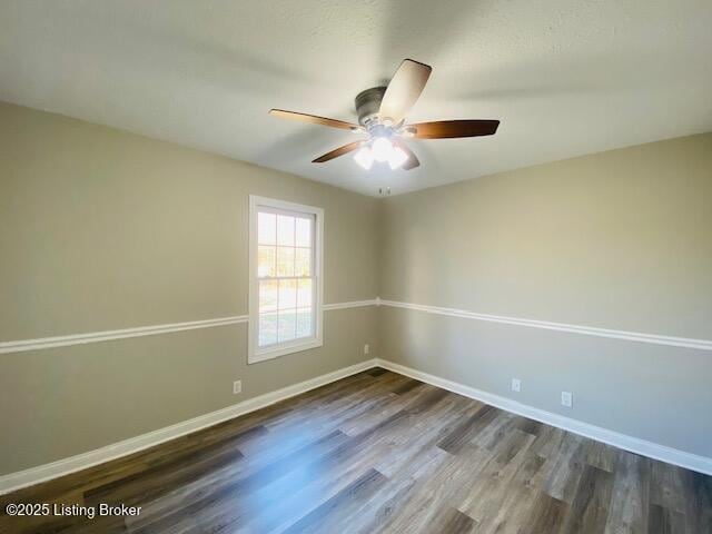 empty room with dark wood-type flooring, baseboards, and ceiling fan