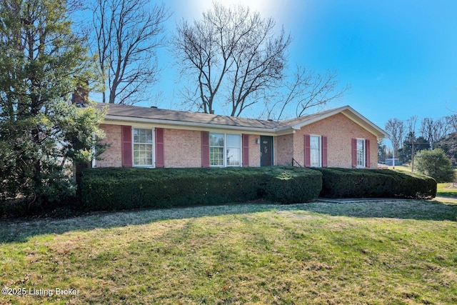 ranch-style home featuring a front yard, brick siding, and a chimney