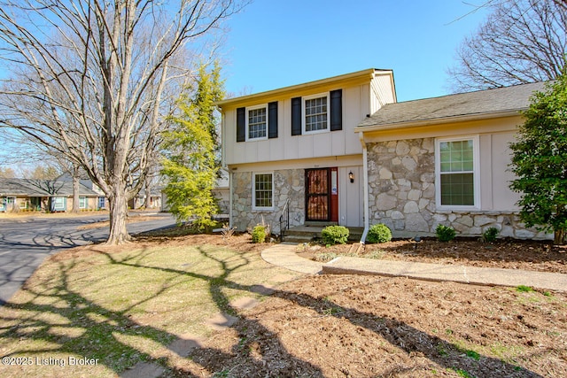 colonial house featuring board and batten siding, stone siding, and roof with shingles