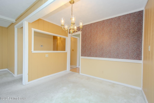 carpeted spare room with wallpapered walls, an inviting chandelier, and a wainscoted wall