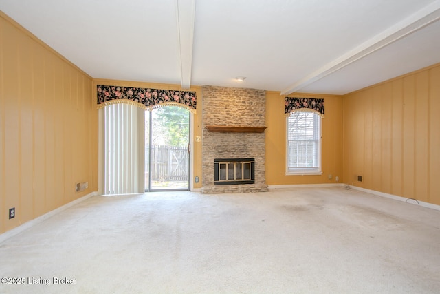 unfurnished living room with a fireplace, beam ceiling, plenty of natural light, and carpet