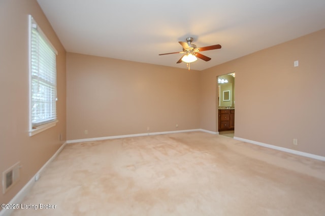 empty room featuring light colored carpet, baseboards, visible vents, and ceiling fan