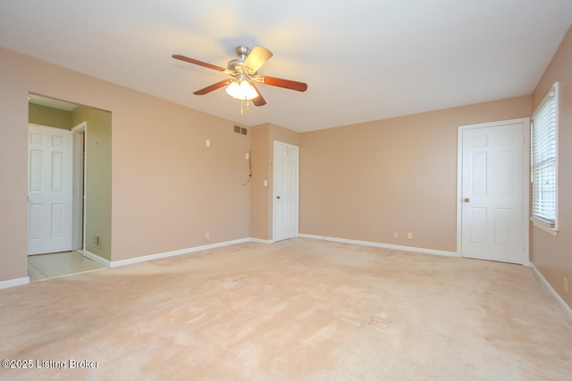 empty room featuring visible vents, a ceiling fan, baseboards, and light carpet