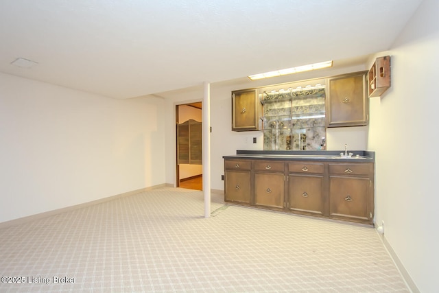 bar featuring a sink, baseboards, light carpet, and wet bar