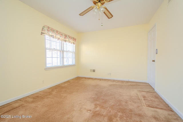 empty room with baseboards, light carpet, visible vents, and a ceiling fan