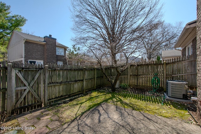 view of yard with fence, central AC, and a gate