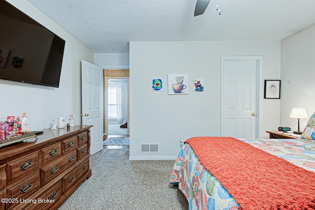 bedroom featuring visible vents, baseboards, carpet, a textured ceiling, and a ceiling fan