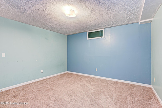 carpeted spare room featuring baseboards and a textured ceiling