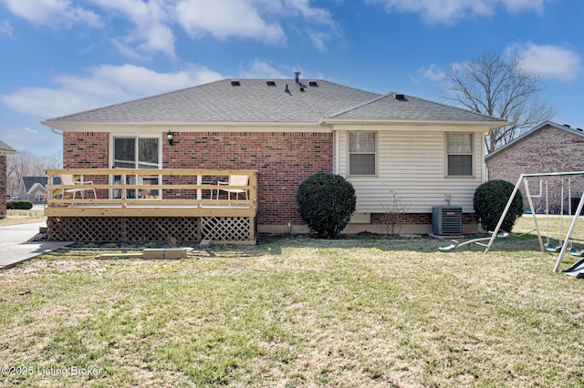 back of property featuring central AC unit, roof with shingles, a wooden deck, a yard, and brick siding