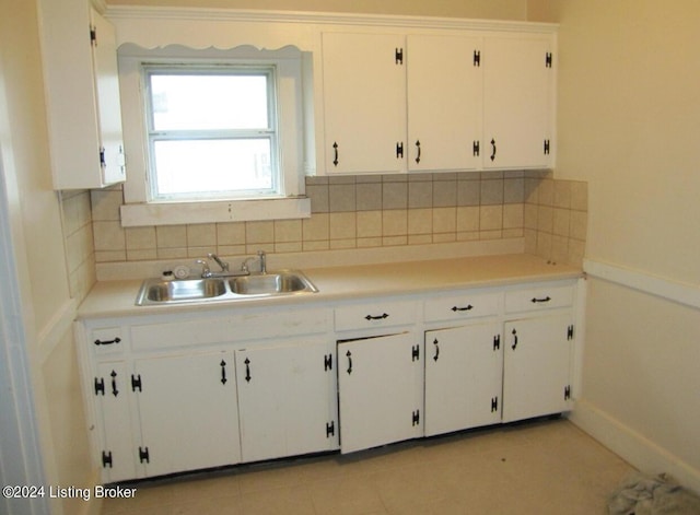 kitchen featuring light tile patterned floors, a sink, light countertops, white cabinetry, and tasteful backsplash