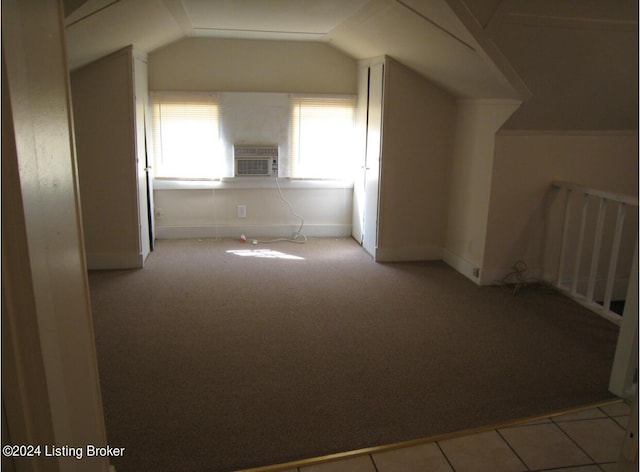 additional living space featuring tile patterned floors, an AC wall unit, carpet, and vaulted ceiling