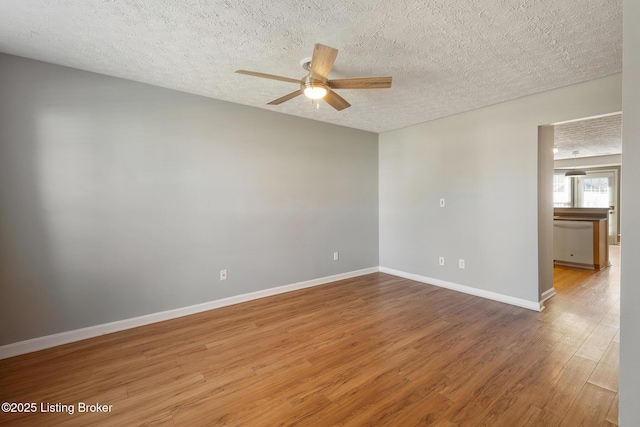 spare room featuring baseboards, a textured ceiling, wood finished floors, and a ceiling fan