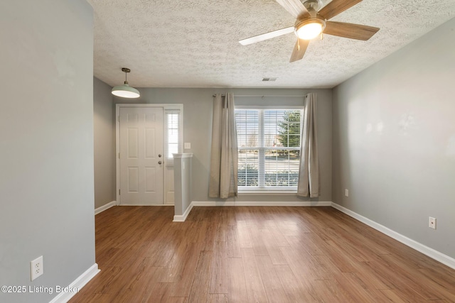 foyer featuring baseboards, a textured ceiling, and wood finished floors