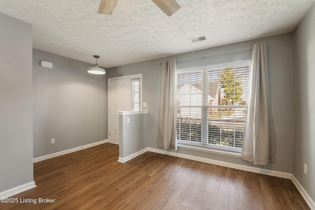 unfurnished room featuring visible vents, wood finished floors, baseboards, and ceiling fan