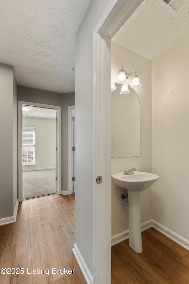 bathroom featuring wood finished floors, baseboards, and a textured ceiling