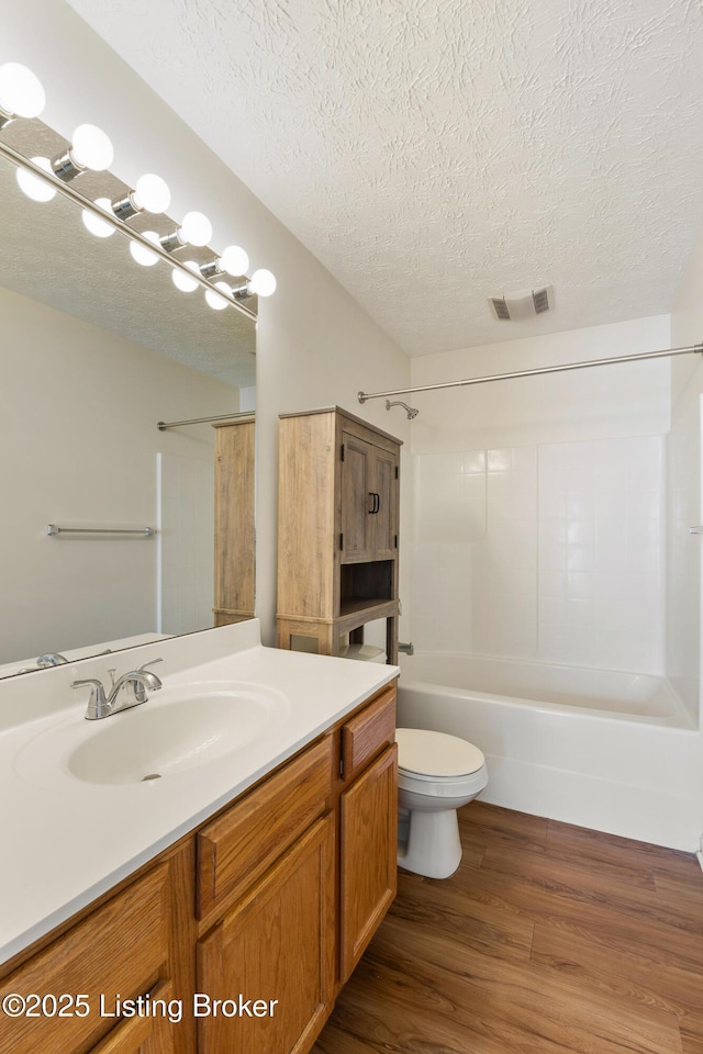 full bathroom featuring visible vents, toilet, a textured ceiling, wood finished floors, and shower / bathtub combination