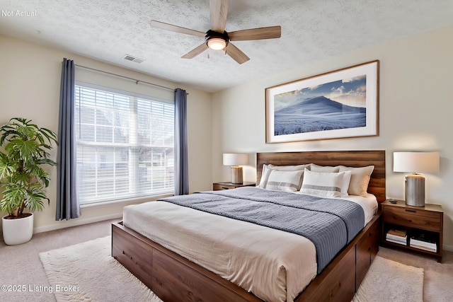 carpeted bedroom featuring visible vents, baseboards, a textured ceiling, and a ceiling fan