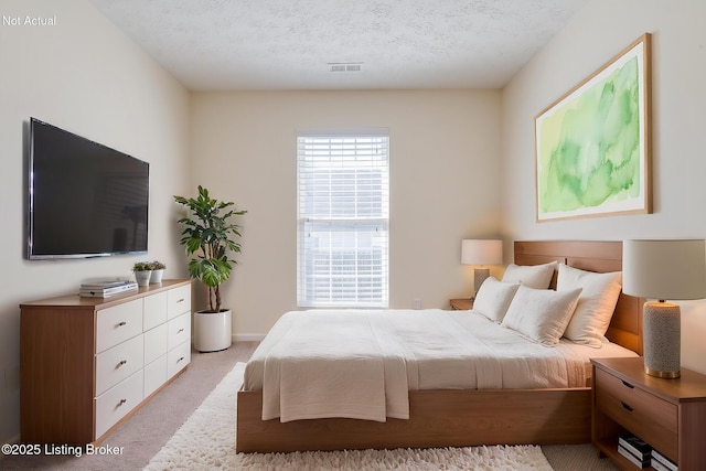 bedroom with visible vents, light colored carpet, and a textured ceiling