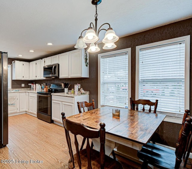 dining area featuring a notable chandelier, recessed lighting, light wood-type flooring, and a wealth of natural light