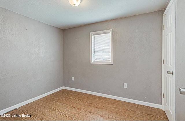 empty room featuring wood finished floors and baseboards