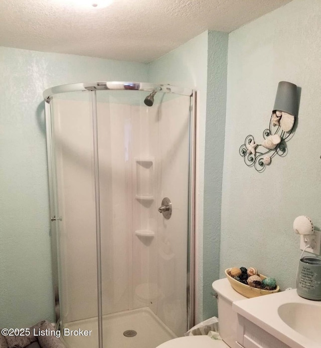 full bathroom featuring a textured wall, a textured ceiling, a shower stall, and toilet