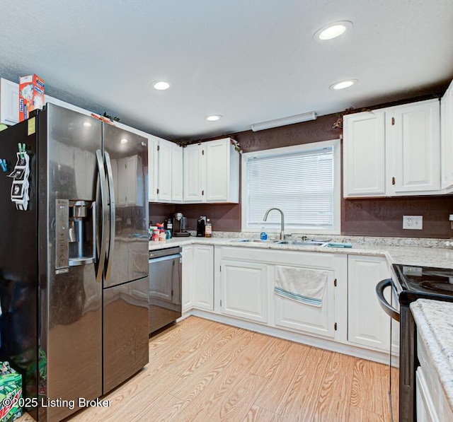 kitchen with dishwashing machine, white cabinets, light wood-style floors, stainless steel fridge, and a sink