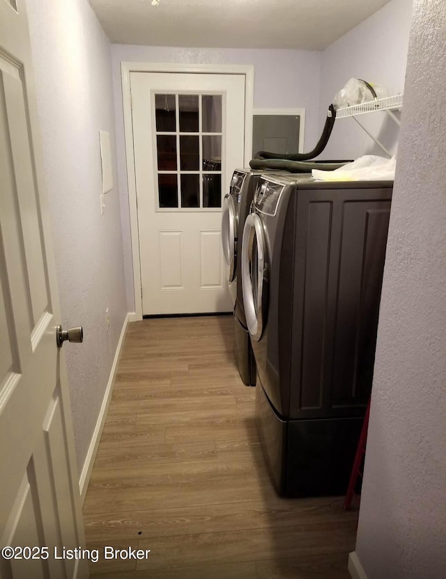 laundry area featuring baseboards, laundry area, light wood-style flooring, a textured wall, and washer and dryer