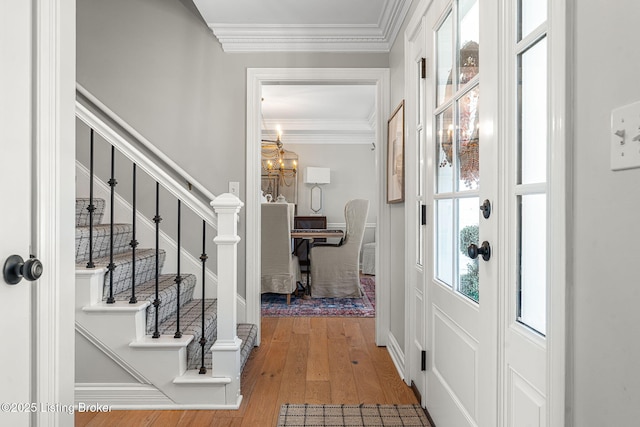 entrance foyer featuring stairway, wood-type flooring, an inviting chandelier, and crown molding