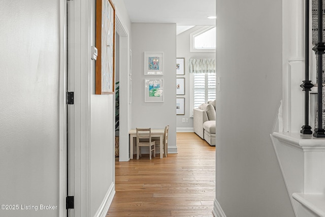 hallway featuring light wood-style flooring and baseboards